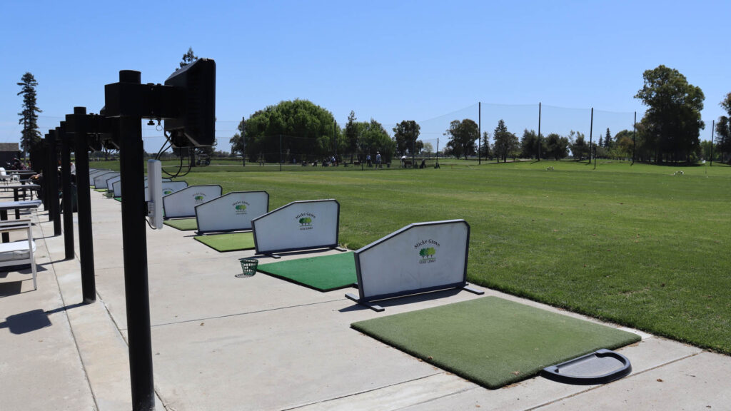Outdoor driving range bays equipped with TrackMan monitors and hitting mats at Micke Grove Golf Links.